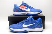 Blue Nike basketball sneakers displayed on a black shoebox, showing the textured upper, white Swoosh, and red number 8.