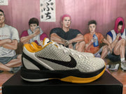 Side view showing the textured white upper, black Swoosh, black midsole, and gold outsole accent.