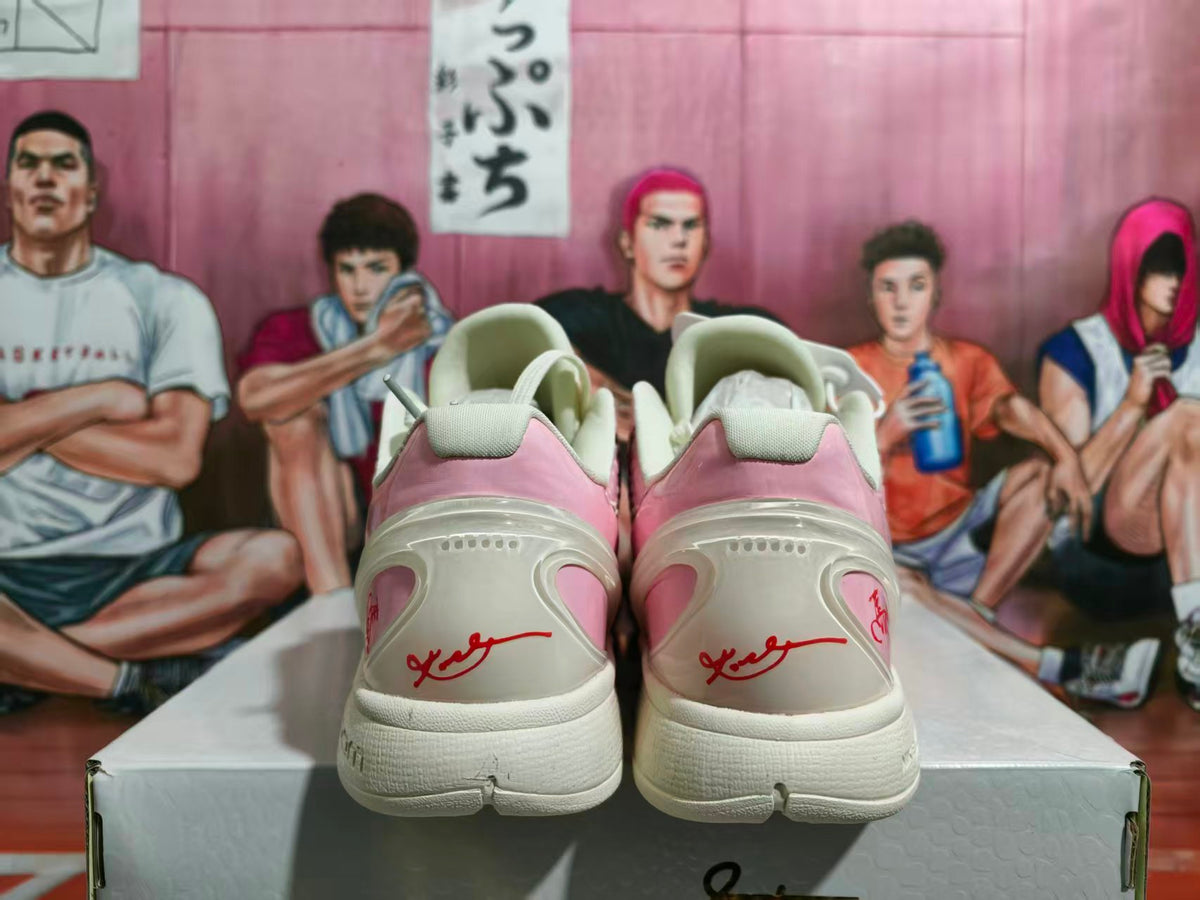 Rear view of pink and off-white Nike basketball sneakers with red heel graphics and Zoom-branded midsoles.