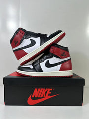 Pair of black, white, and red high-top sneakers displayed on a shoebox.