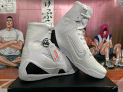 Angled view of white high-top basketball shoes showing side panels, laces, and heel details