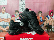 Angled view of black Nike sneakers showing the side panels, swoosh branding, and sculpted soles.