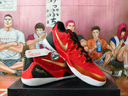Red and gold basketball shoes shown from the side and at an angle, with a gold Swoosh and patterned heel.