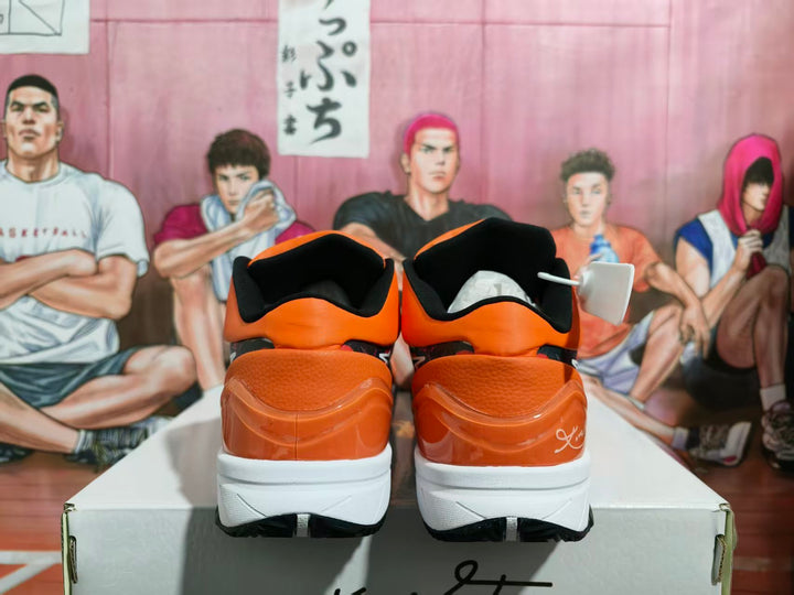 Rear view of orange and black Nike basketball sneakers with white midsoles and black outsoles, displayed on a shoebox.