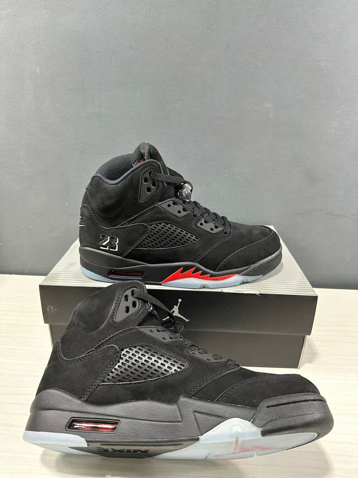 Pair of black Air Jordan 5 high-top sneakers with red midsole accents displayed on a black shoe box.