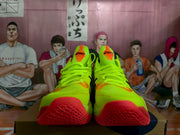 Front view of the fluorescent green shoe pair showing orange tongue accents, laces and red outsole sections.