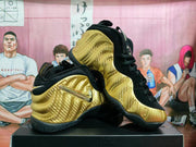 Two gold and black Nike sneakers displayed together, showing the side panels, padded collars, laces, and outsoles.