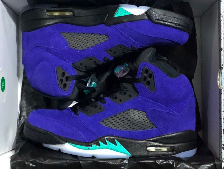 Pair of purple and black high-top sneakers shown in an open shoe box, with turquoise midsole accents and translucent outsoles.