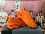 Pair of orange Nike Air Max 1000 sneakers displayed on a black shoebox, showing the sculpted side panels and treaded outsole.