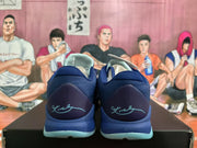 Rear view of a pair of dark blue basketball sneakers with light blue outsole accents and illustrated basketball backdrop.