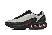 Side profile of light gray, black and red Nike Air Max DN sneakers.