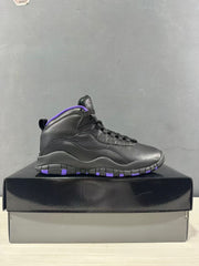 Side profile of a black high-top sneaker with purple outsole accents on a shoebox.