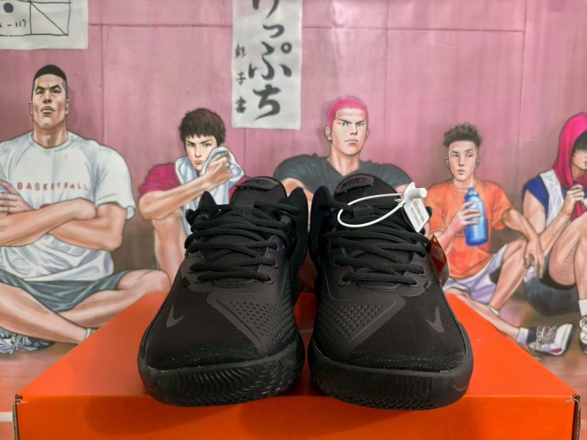 Front view of a pair of black Nike basketball sneakers with black laces and textured toe panels on an orange box.