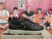 Side profile of a black sneaker with a curved white stitched graphic and contrasting light-colored sole.