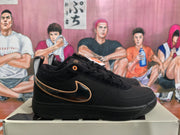 Side profile of a black Nike Book 1 sneaker showing the dark glossy Swoosh with tan-gold edging and a black sole.