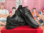 Angled view of paired black basketball sneakers showing the contrasting Nike Swoosh, gold tongue emblem, and layered upper.