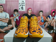Front view of yellow Nike basketball shoes with purple tongue logos, yellow laces, and patterned uppers.