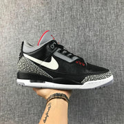 Side profile of a black and grey Jordan sneaker with a white Swoosh, elephant-print overlays, and visible heel air unit.