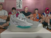 Side view of a grey Jordan basketball sneaker showing patterned side panels, teal midsole accents and a padded collar.