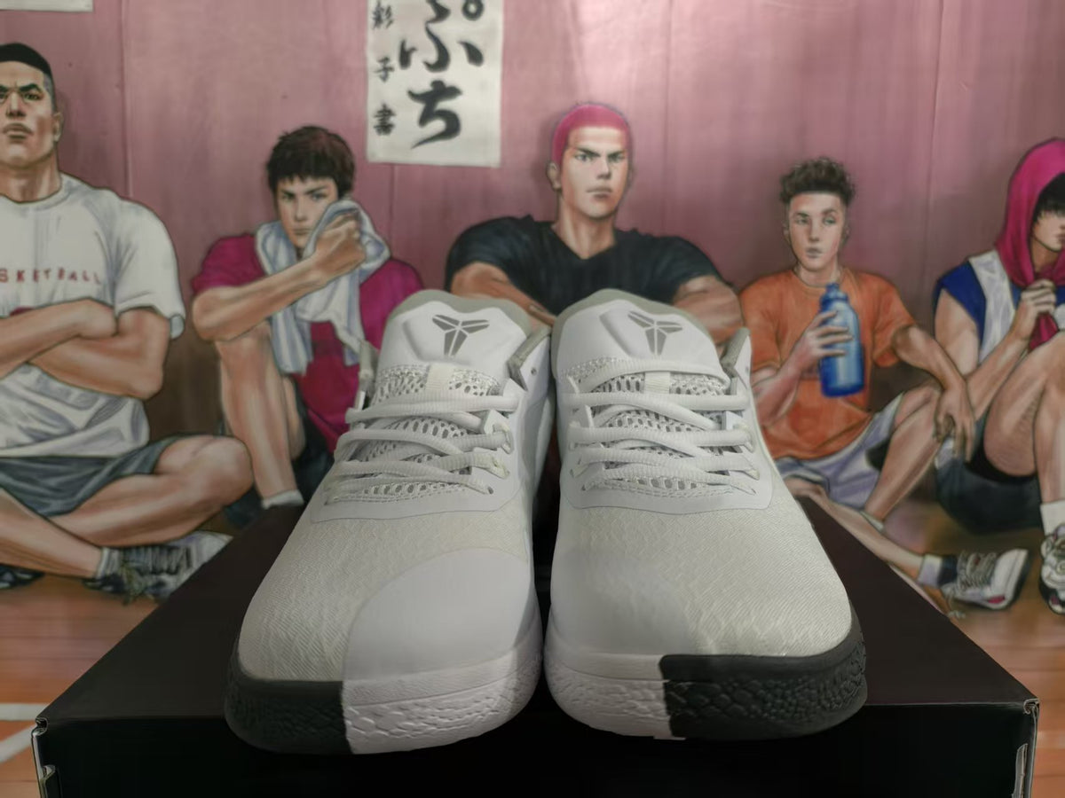 Front view of white and gray basketball sneakers showing the laces, tongue logos, textured uppers, and black outsole sections.