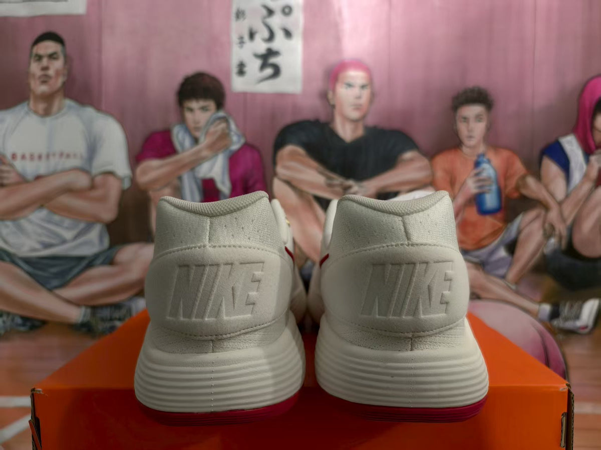 Rear view of white Nike sneakers with embossed heel branding and red outsoles on an orange box.