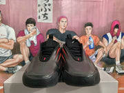 Front view of black sneakers with perforated toe areas and red details.