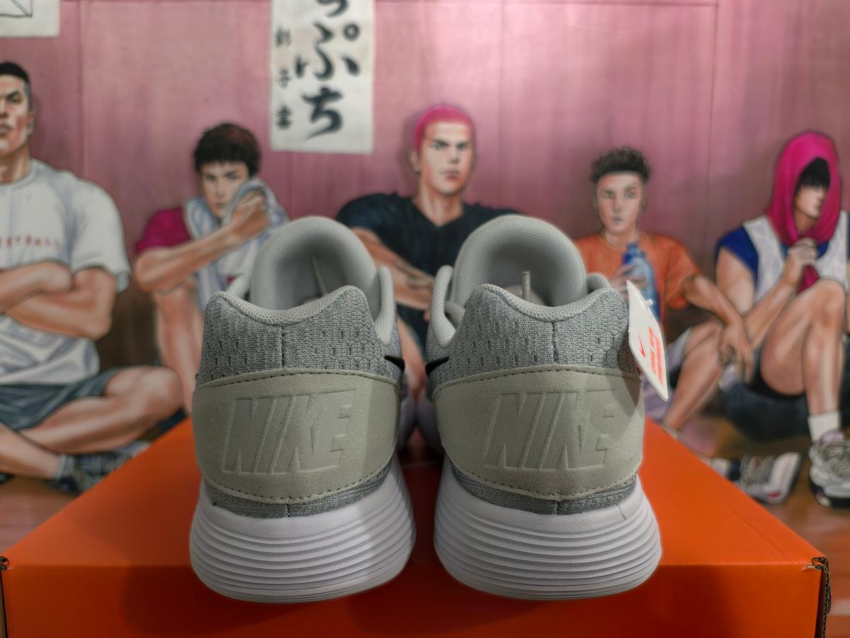Rear view of gray Nike sneakers showing the padded collars, embossed heel branding, and white ribbed soles.