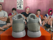 Rear view of gray Nike sneakers showing the padded collars, embossed heel branding, and white ribbed soles.