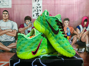 Angled view showing the green textured uppers, black and pink Swoosh branding, and neon soles.