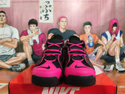 Front view of black and bright pink Nike sneakers with lace-up fastening