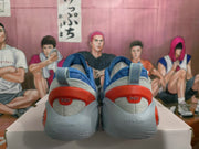 Rear view of blue sneakers with gray heel panels and red heel accents on a box.