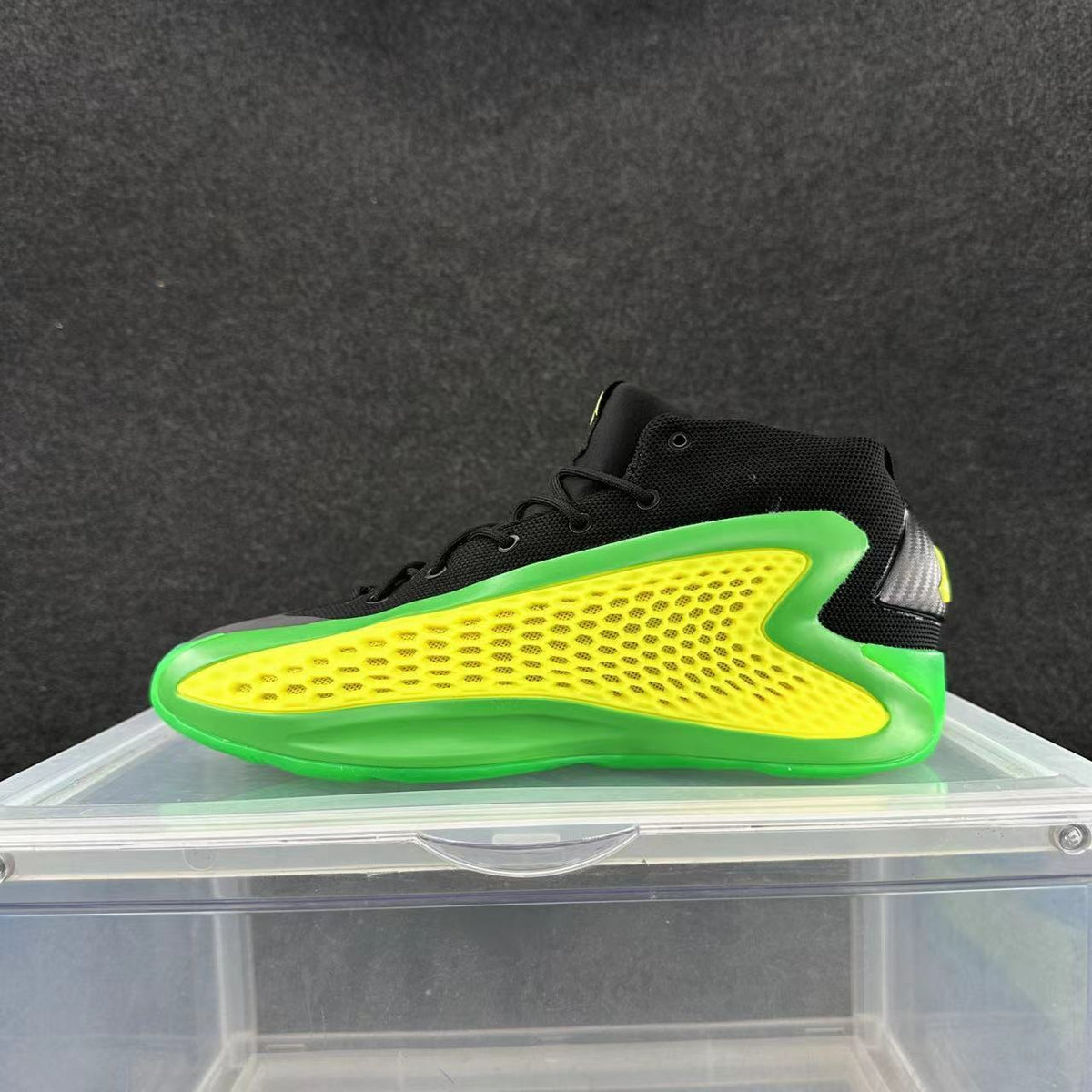 Side view of a black high-top basketball sneaker with a bright green sole and trim and a perforated yellow side panel.