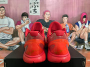 Rear view of red Nike basketball sneakers showing padded collars, translucent red-orange heel sections, and a basketball-themed background.