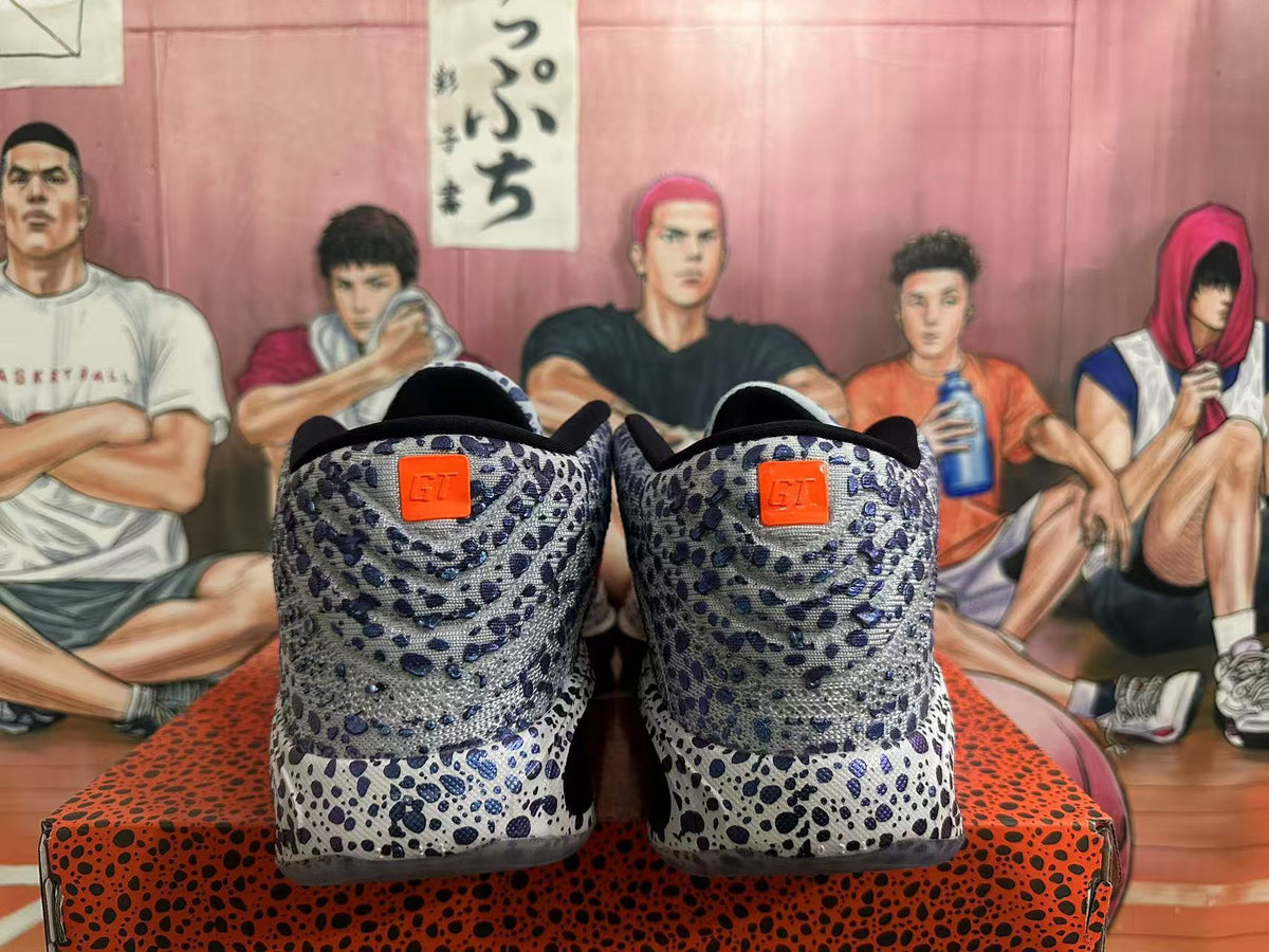 Rear view of gray Nike basketball shoes with blue and black speckling and orange heel tabs.