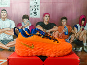 Profile of an orange Nike sneaker with blue accents, patterned laces, and a sculpted sole.