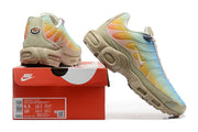 Nike Air Max Plus sneakers beside a box with a visible product label