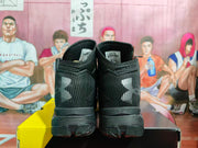 Rear view of black and gray high-top basketball sneakers showing Under Armour branding, textured uppers, and heel panels.