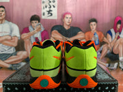 Rear view of fluorescent green Nike sneakers with orange heel accents, black trim, and teal outsole details on a patterned box.