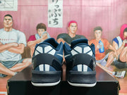 Rear view of navy and black Nike basketball sneakers showing contrasting heel panels, graphic details, and white outsole edges.
