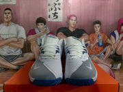 Front view of white and blue Nike basketball sneakers with white laces, gray forefoot panels, and blue rubber outsoles.