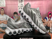 Angled view of a pair of silver Nike sneakers highlighting the sculpted white soles and circular cushioning elements.