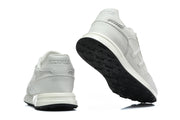 Rear and outsole views of white sneakers with black tread.