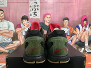 Rear view of camouflage Nike basketball shoes showing black collars, olive green heel panels, and red heel detailing.