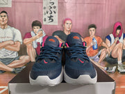 Front view of a pair of dark navy Nike basketball sneakers with pink accents, dark laces, and white toe midsoles.