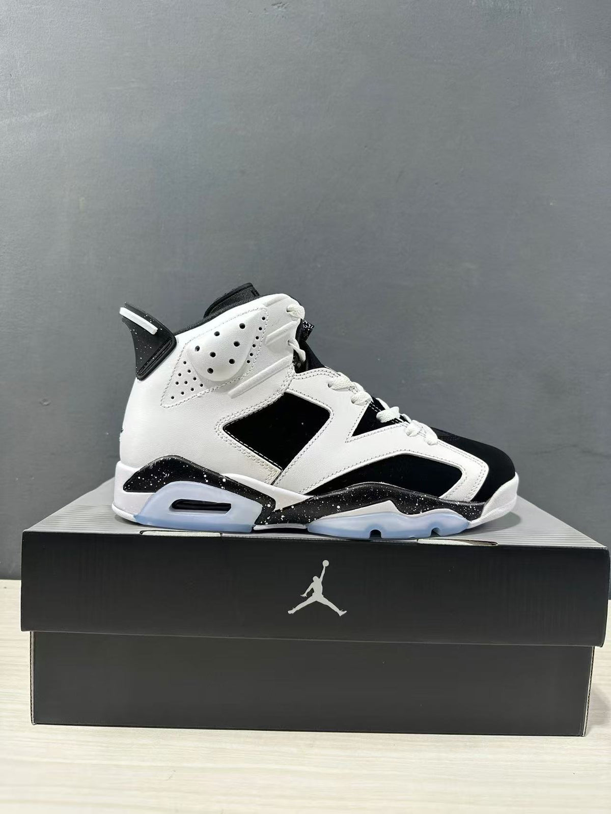Side view of a white and black Jordan Air Jordan 6 high-top sneaker displayed on a black shoebox.