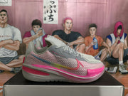 Gray and pink Nike GT basketball sneaker shown in side profile on a shoebox.