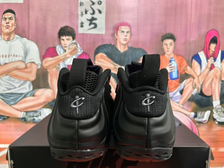 Rear view of a pair of black Nike sneakers showing padded collars, pull tabs, textured heel panels, and sculpted outsoles.