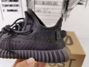 Side close-up showing the dark textured upper, heel pull tab, and ribbed outsole.