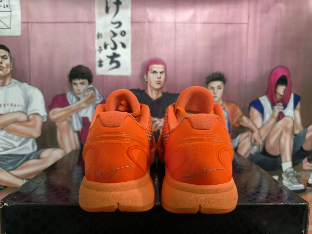 Rear view of a pair of bright orange Nike basketball sneakers showing padded collars, orange midsoles, and signature-style heel graphics.