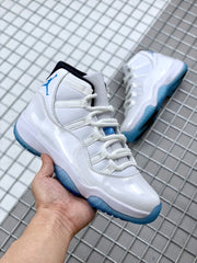 Three-quarter view of the white and blue Jordan 11 sneaker held in hand.